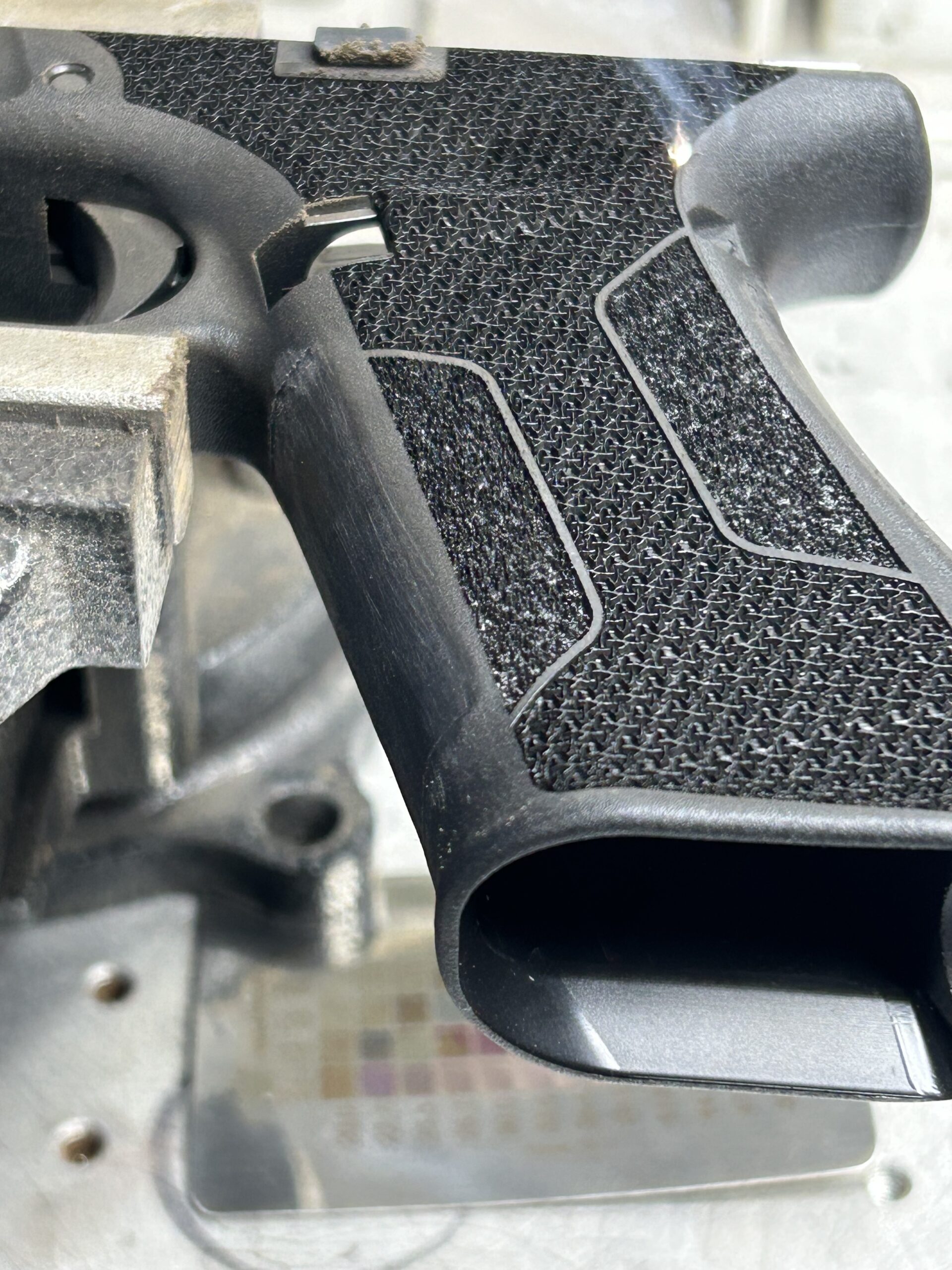 Custom laser stippling on a polymer pistol frame grip for enhanced texture and control at Chesapeake Gunslingers.