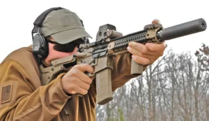 Shooter firing a suppressed SBR on the range, demonstrating an NFA item with a rifle-mounted suppressor.
